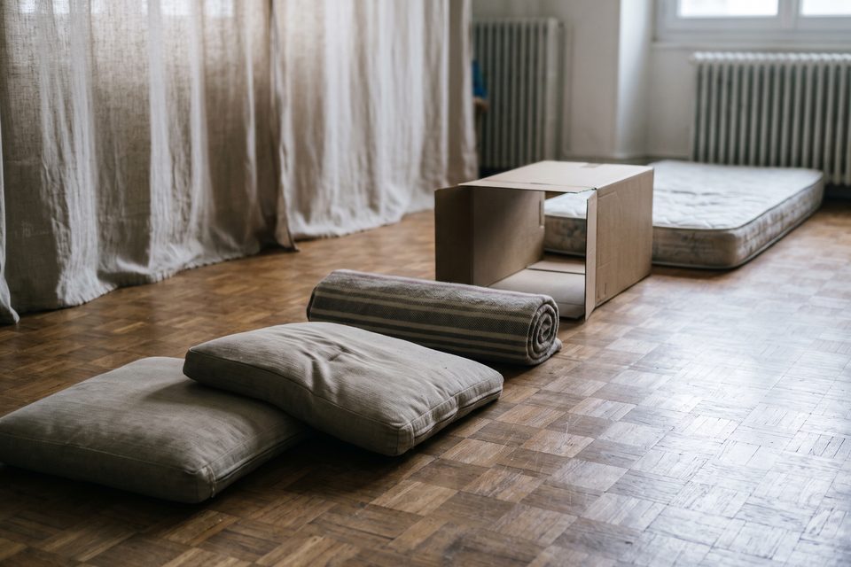 Parcours fait de coussins de canapé, d'une couverture roulée et d'un tunnel en carton sur un parquet de chêne, rideau de lin en fond